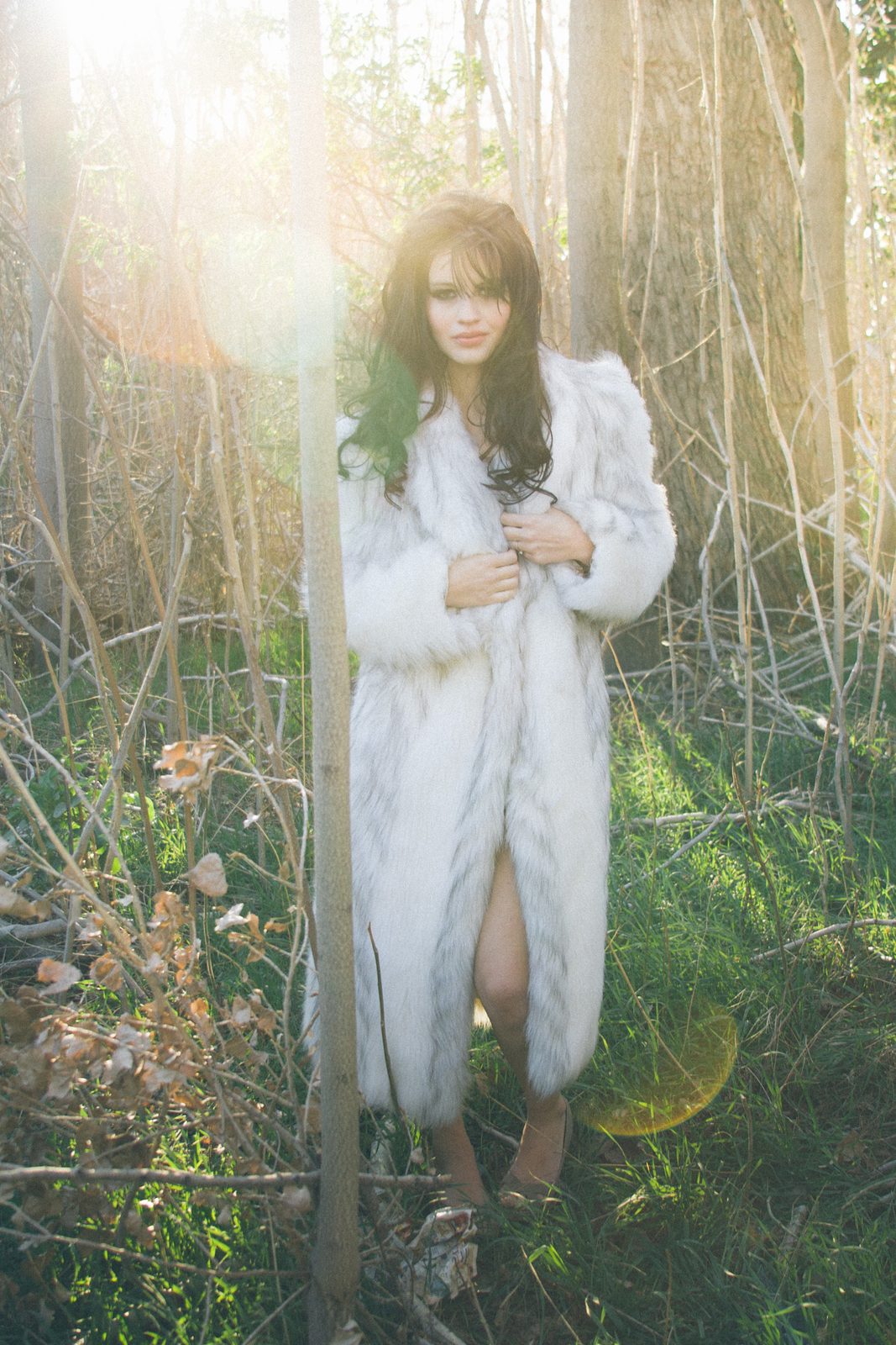 Woman in a white fur coat among tall reeds